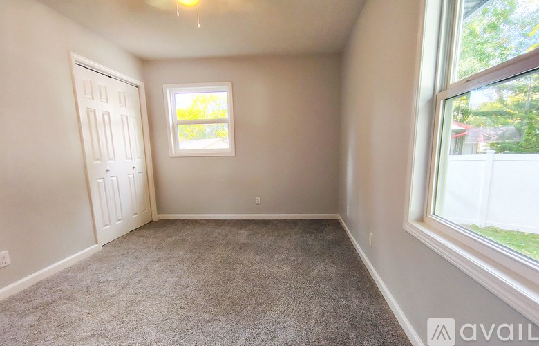 A room with a carpeted floor, a window, and a door.