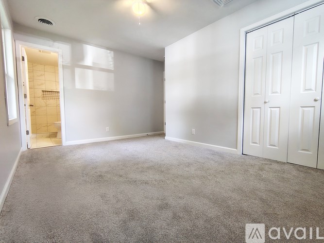 A spacious room with white walls and carpeted floor.