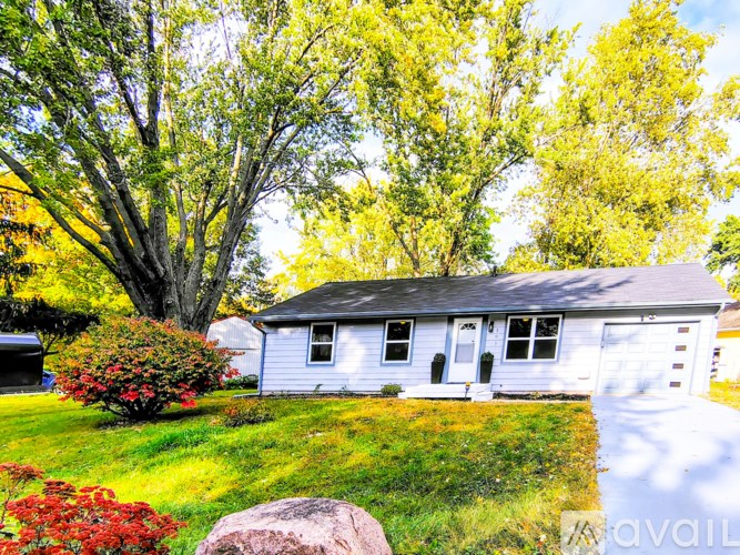 A house with a white garage door and a large tree in front.