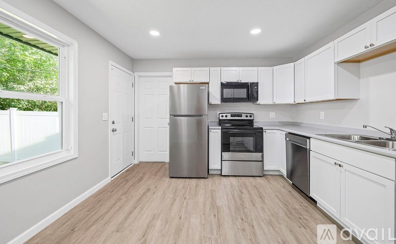 A kitchen with white cabinets and a wooden floor.