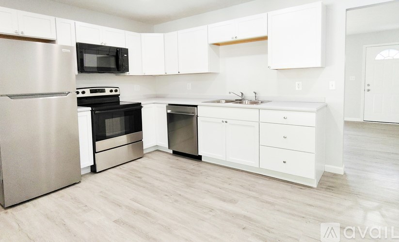A kitchen with white cabinets and a wooden floor.