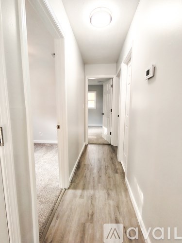 A hallway with a carpeted floor and white walls.