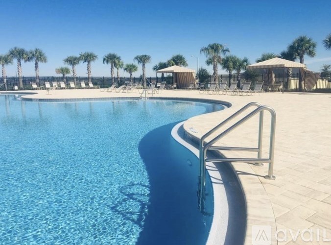 A swimming pool with a metal railing and palm trees in the background.