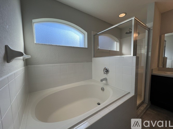 A bathroom with a white tub and a window above it.