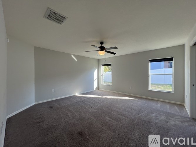 A spacious room with a ceiling fan and carpeted floor.