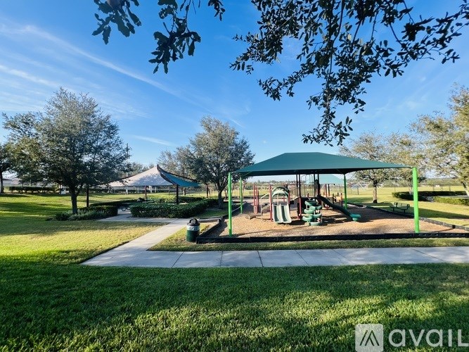 A playground with a green canopy and a slide.