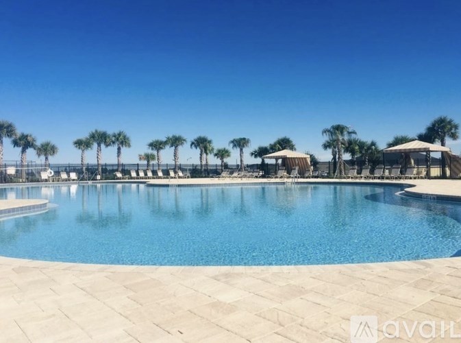 A large swimming pool surrounded by palm trees and a clear blue sky.