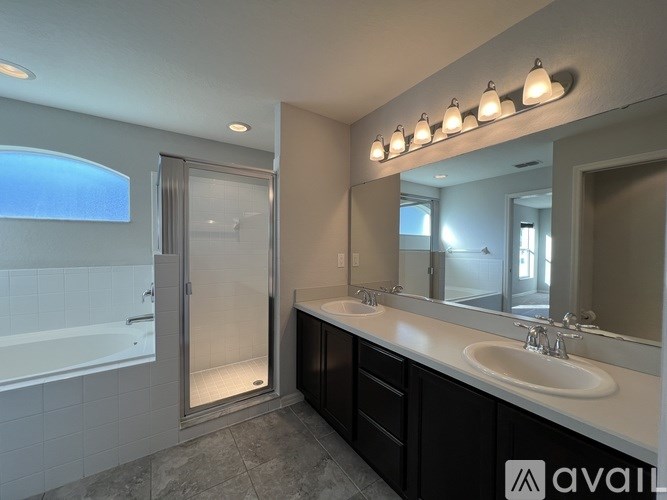 A bathroom with a tub, sink, mirror, and lights.