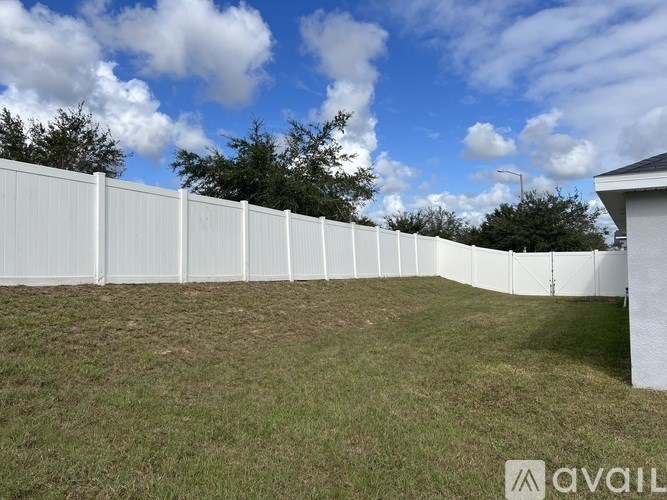 A white fence encloses a grassy yard.