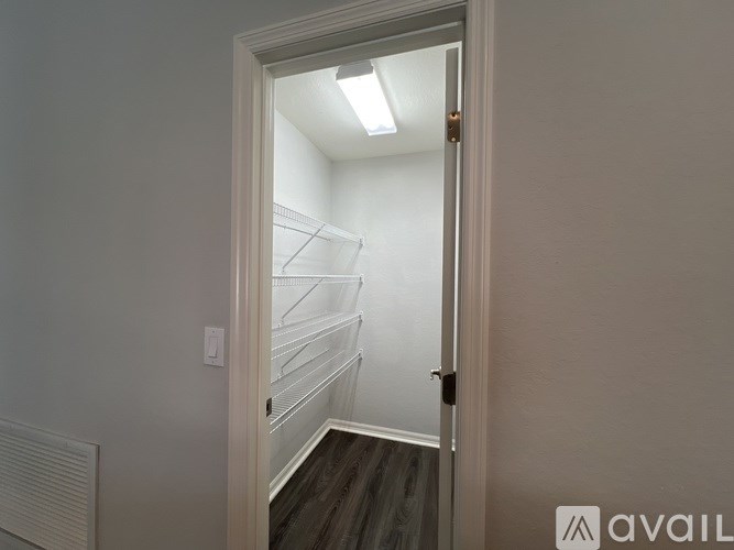 A white door with a gold handle is open to a small, empty room with a white wall and a radiator.