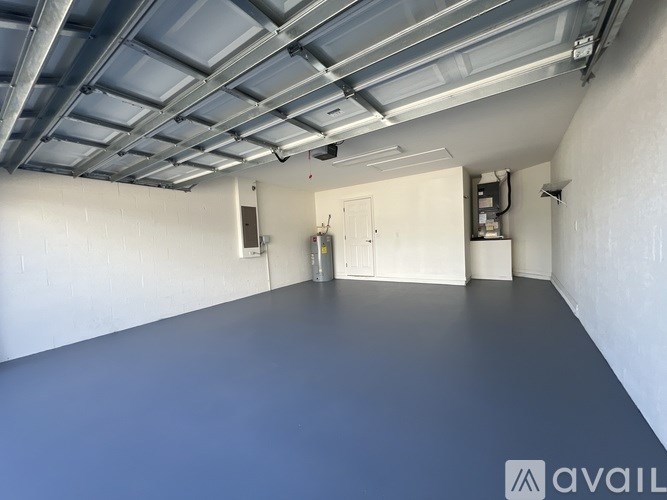A spacious room with a grey floor and a white ceiling with exposed pipes.