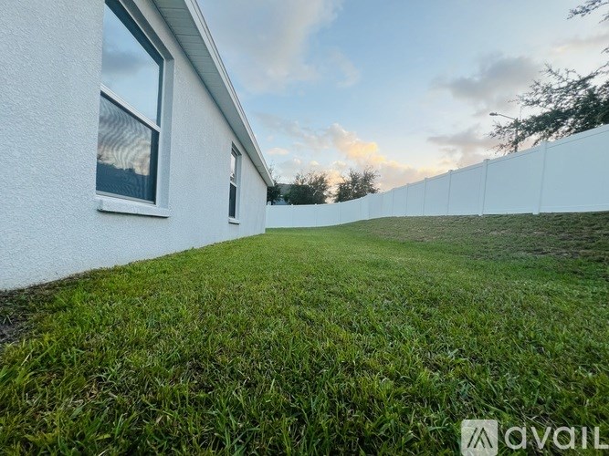 A white house with a window and a green lawn in front.