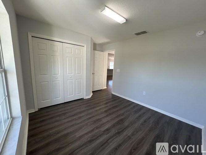 A room with a white door and wooden flooring.