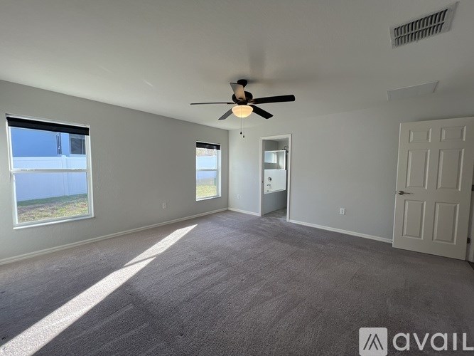 A spacious room with a ceiling fan and carpeted floor.