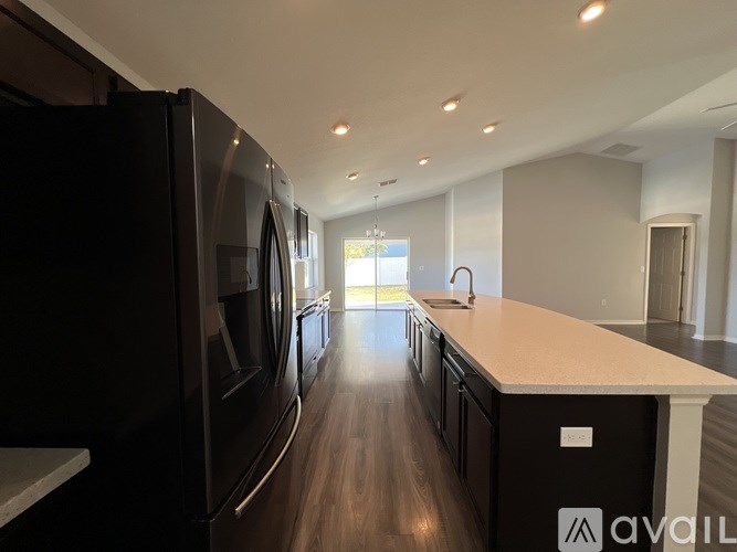 A modern kitchen with black appliances and wooden floors.