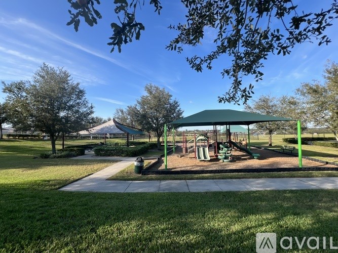 A playground with a green canopy and a slide.