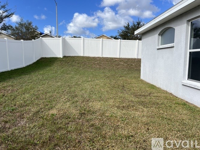 A white fence surrounds a grassy yard.