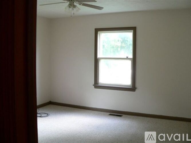 A room with a window and a fan on the ceiling.