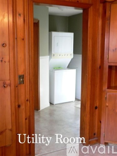 A utility room with a white fridge and wooden doors.