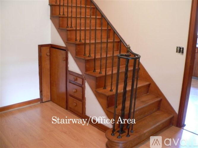 A wooden staircase with a black railing and a cabinet underneath it.