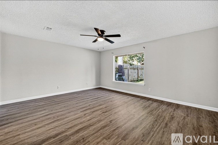 A room with a ceiling fan and wooden flooring.