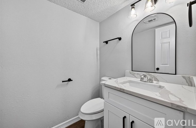 A bathroom with a toilet, sink, and mirror.