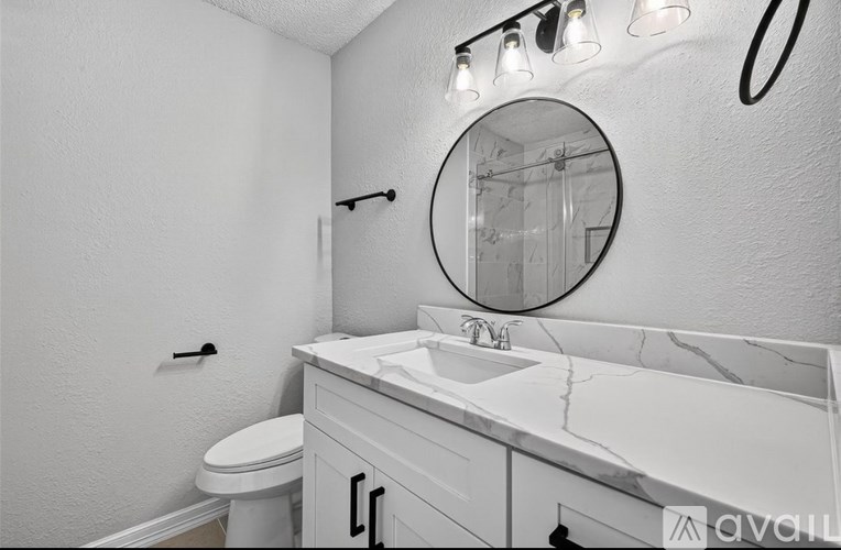 A bathroom with a white toilet and a marble countertop.