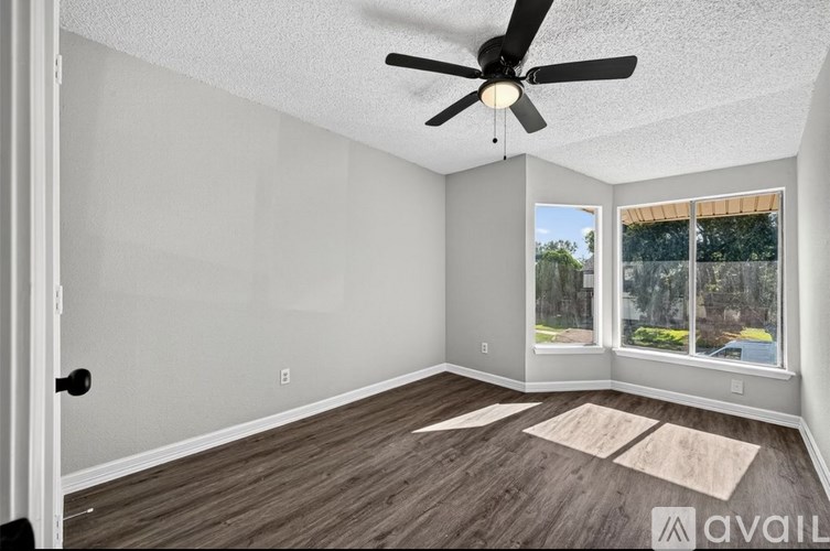 A room with a ceiling fan and a rug on the floor.