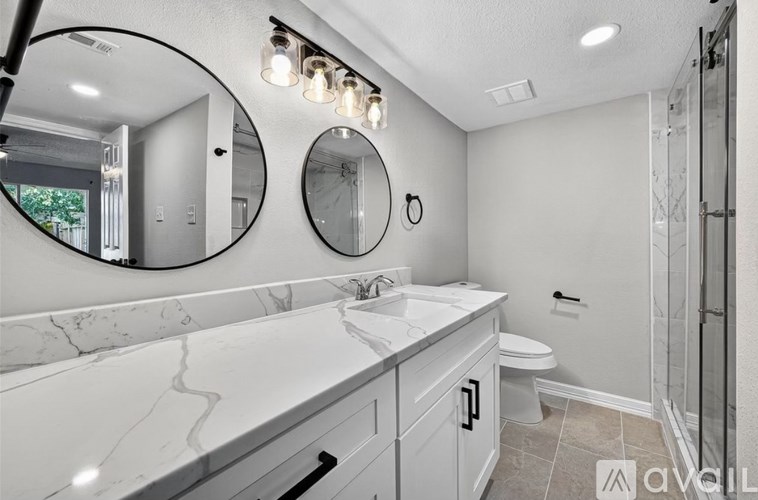 A bathroom with a marble countertop and a walk-in shower.