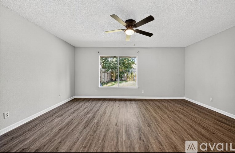 Empty room with a ceiling fan and a window showing an outdoor view.