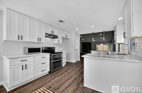 A kitchen with white cabinets and a wooden floor.