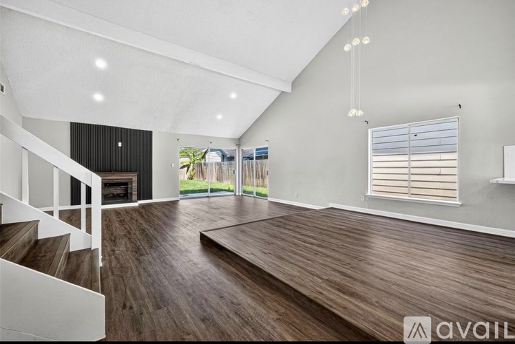 A spacious room with wooden floors and a staircase leading to the upper level.