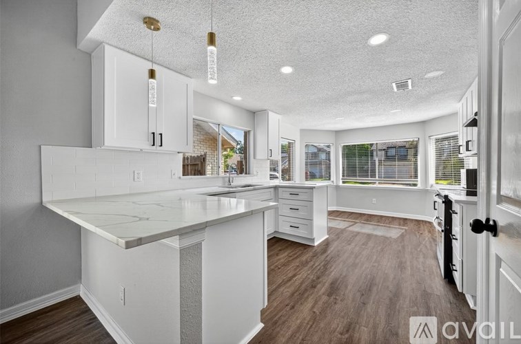 A kitchen with white cabinets and a marble countertop.