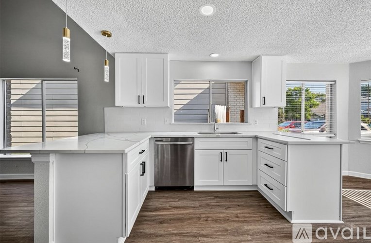 A modern kitchen with white cabinets and a wooden floor.