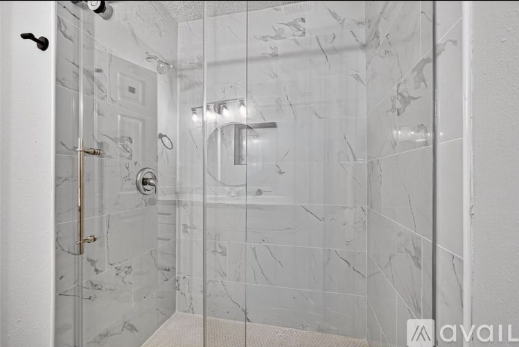 A bathroom with a marble tile shower and a glass door.