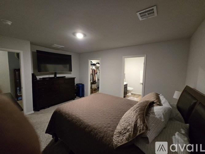 A bedroom with a bed, dresser, and a television.