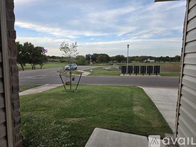 A view from a window looking out to a green lawn and a parking lot.
