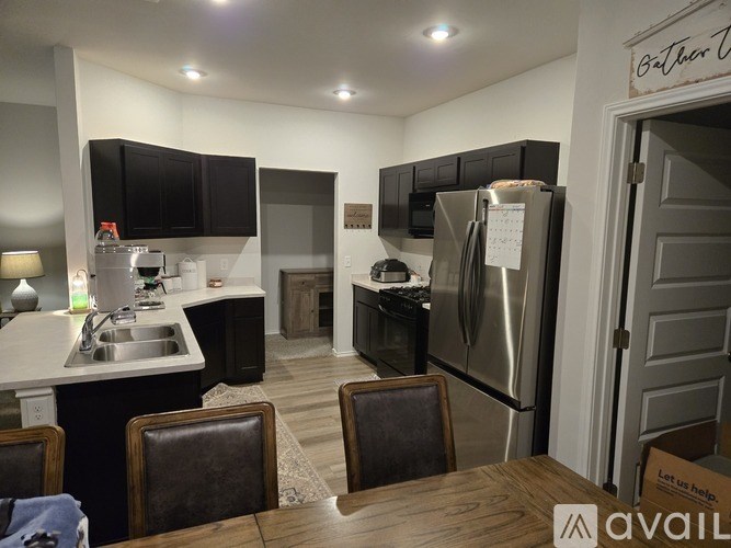 A kitchen with a refrigerator, sink, and cabinets.