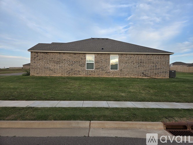 A house with a brown brick exterior and a grey roof is for sale.