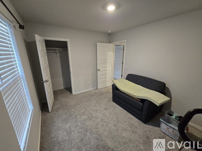 A bedroom with a bed, couch, and two doors.