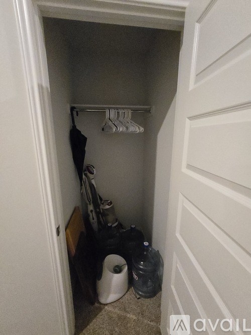 A small closet with a white shelf and clothes hanging on it.