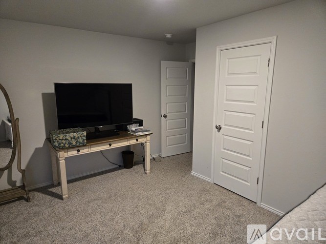 A living room with a white door and a wooden bench with a television and remote on it.