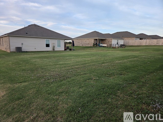 A grassy field with two houses and a fence in the background.