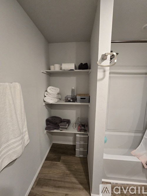 A bathroom with a towel hanging on the wall and towels on a shelf.