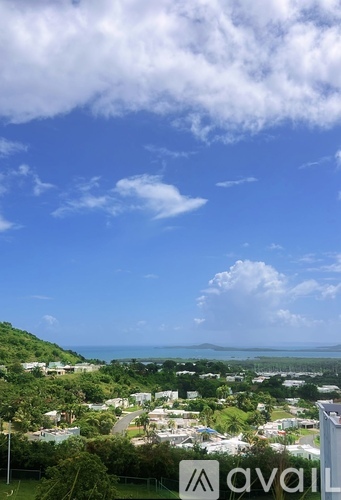 A view of a residential area with houses and greenery under a partly cloudy sky.