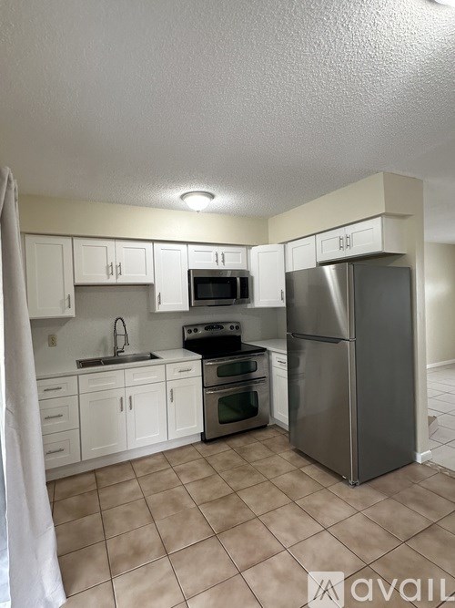 A kitchen with white cabinets and a stainless steel refrigerator.