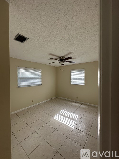A room with a ceiling fan and two windows.