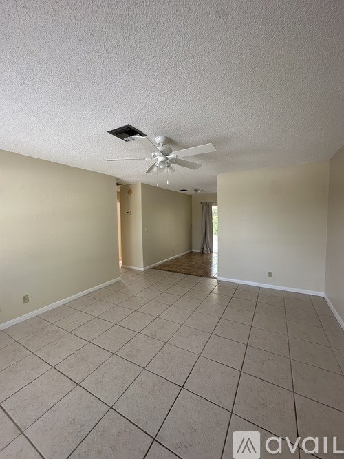 A spacious room with a ceiling fan and tiled flooring.