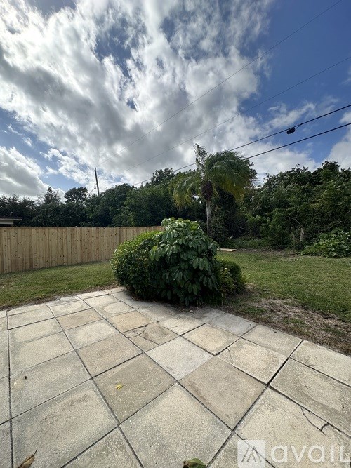A backyard with a tiled patio and a wooden fence.