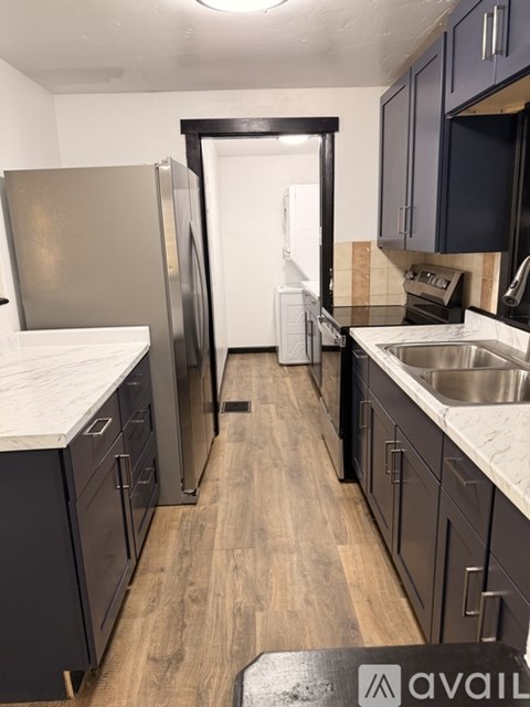 A kitchen with a refrigerator, sink, and cabinets.